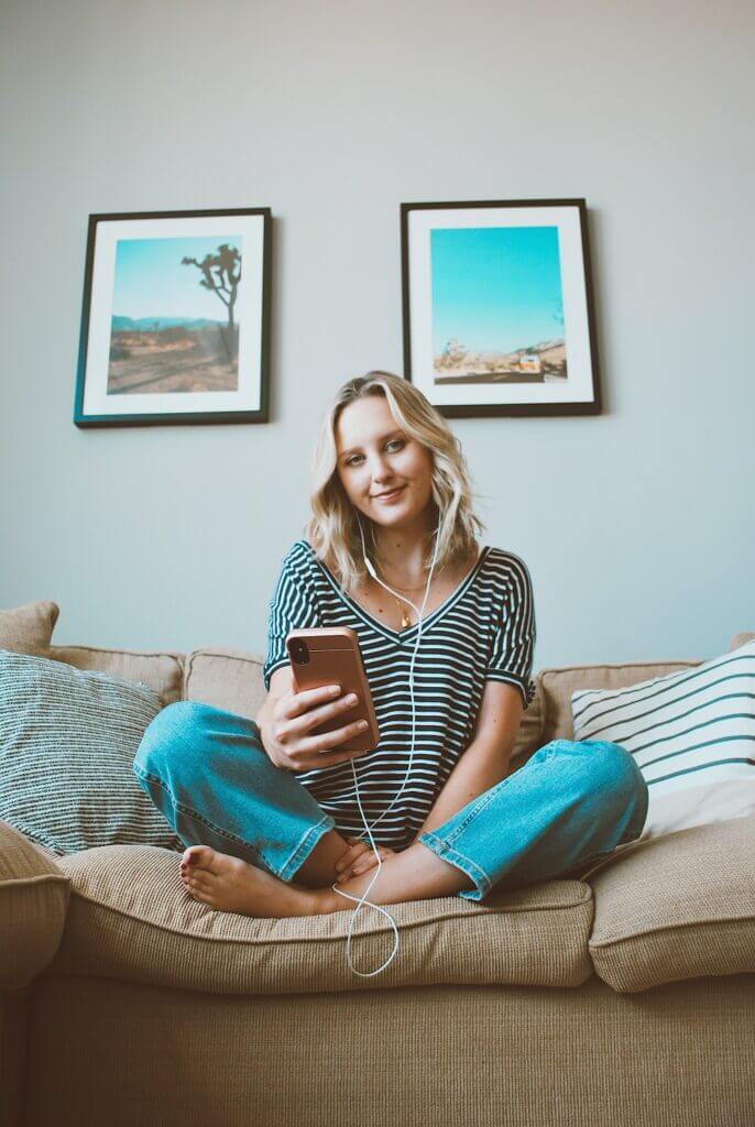 Blonde woman listening to a podcast on the couch