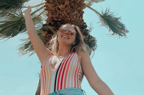Posing in front of a palm tree protected from the sun with her beauty essentials