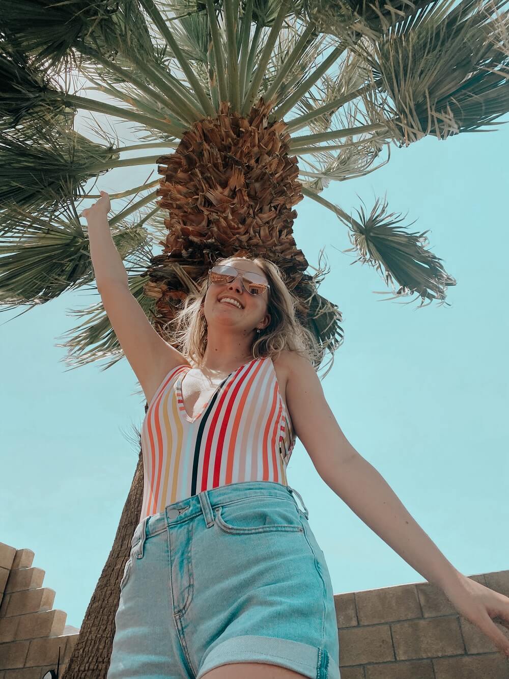 Posing in front of a palm tree protected from the sun with her beauty essentials