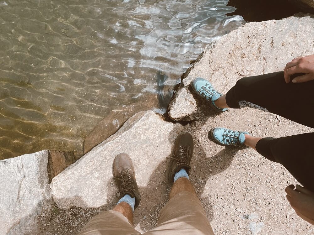 Hiking shoes next to a clear water lake in the Rocky mountains